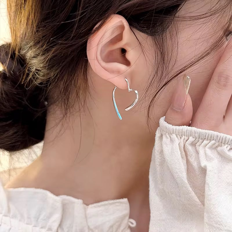 Close-up of a person wearing a silver hoop earring with a blue accent.