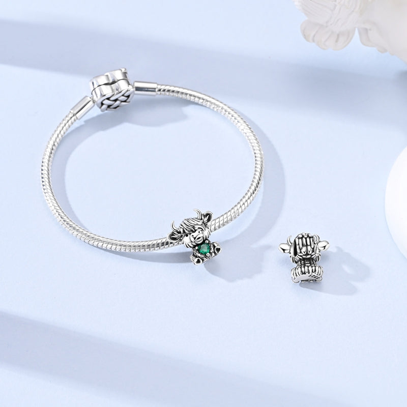 Silver Highland cow charm with emerald green heart crystal and detailed fur design