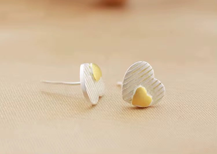 Heart-shaped earrings with gold centers on a beige fabric background