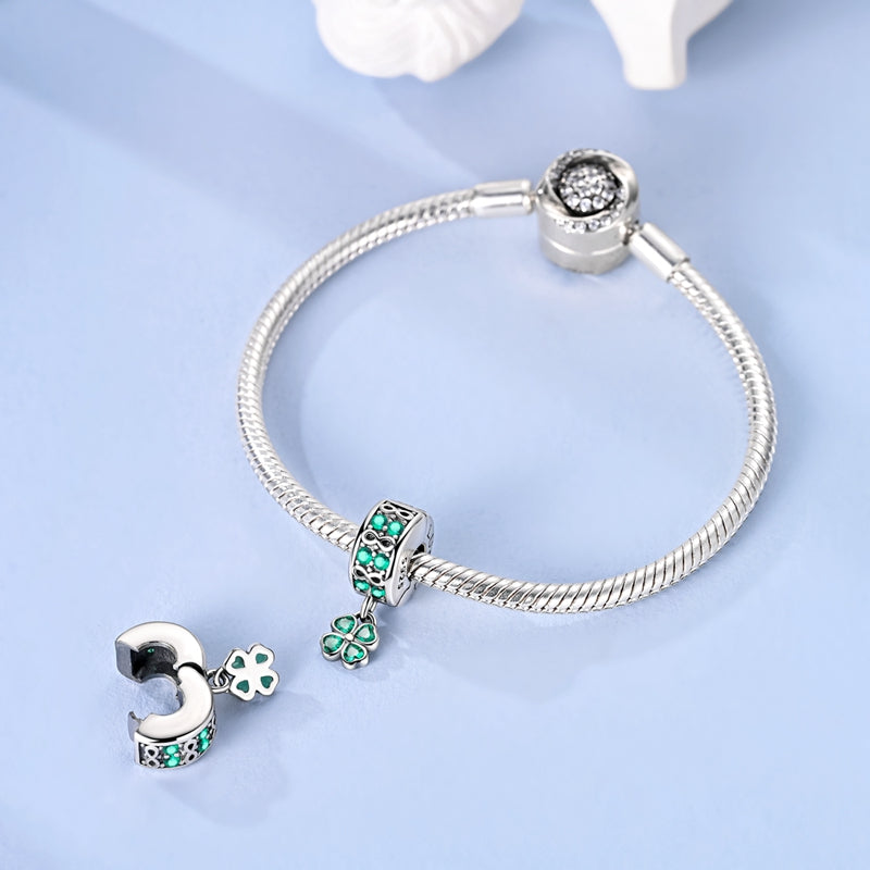 Silver clip-on charm with green crystals, infinity symbols and dangling four-leaf clover