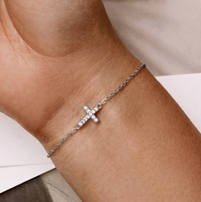 Dainty silver cross bracelet with sparkling crystals on wrist, minimalist adjustable chain jewelry