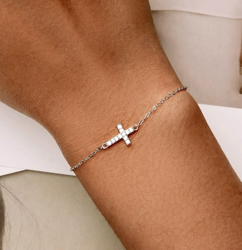 Dainty silver cross bracelet with sparkling crystals on wrist, minimalist adjustable chain jewelry