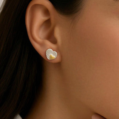 Close-up of an ear wearing a gold earring with a heart design.