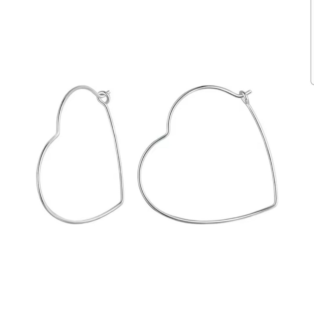 Minimalist heart-shaped hoop earrings in sterling silver worn on ear, thin elegant design