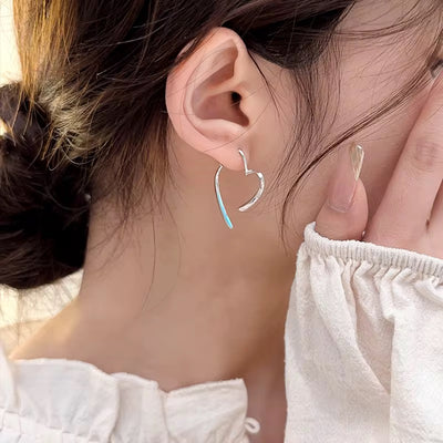 Close-up of a person wearing a silver hoop earring with a blue accent.