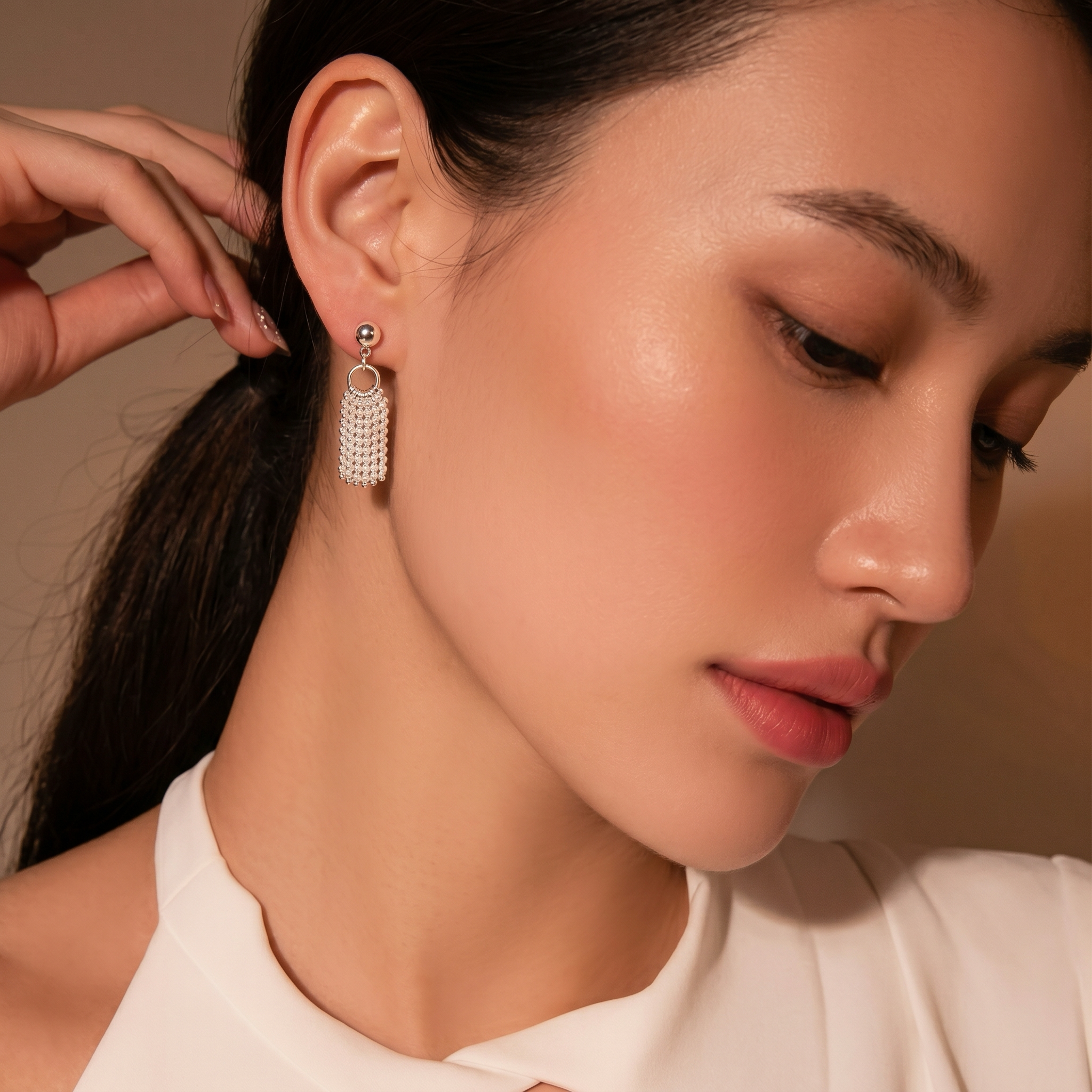 Close-up of a woman wearing a pearl earring with a neutral background